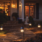 Black solar-powered 2pk garden light shepherd hook with warm glowing glass lanterns illuminating a stone walkway