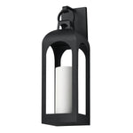 A black metal lantern-style wall sconce with a white cylindrical candle insert, shown against a plain white background.