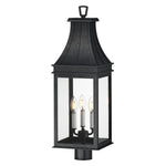 A black outdoor lantern-style wall light with three candle-style bulbs visible inside clear glass panels, shown against a plain white background.