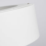 Close-up of a white cylindrical lampshade or container with a smooth matte finish, showing a small metal screw detail at the top against a light gray background.