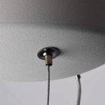 Close-up of a ceiling light fixture with a textured gray shade and visible wiring.