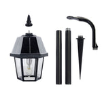 Black solar-powered garden light shepherd with clear glass panels and hexagonal frame on shepherd hook for outdoor use