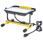 A portable work light with a yellow and black metal stand, featuring a white diffuser panel on top, a yellow handle, and an attached black power cord with a US plug, shown on a white background.