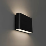 A modern black rectangular wall sconce light fixture mounted on a gray wall, casting a warm light downward and upward.