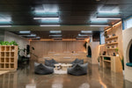 Gray beanbag chairs with plush fabric in a modern lounge featuring a 4 ft direct indirect led louver beam fixture with selectable color temperature