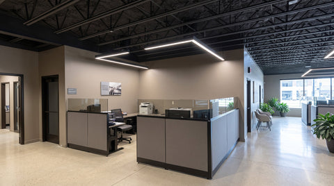 Suspended linear LED fixtures in a commercial office with a dark ceiling