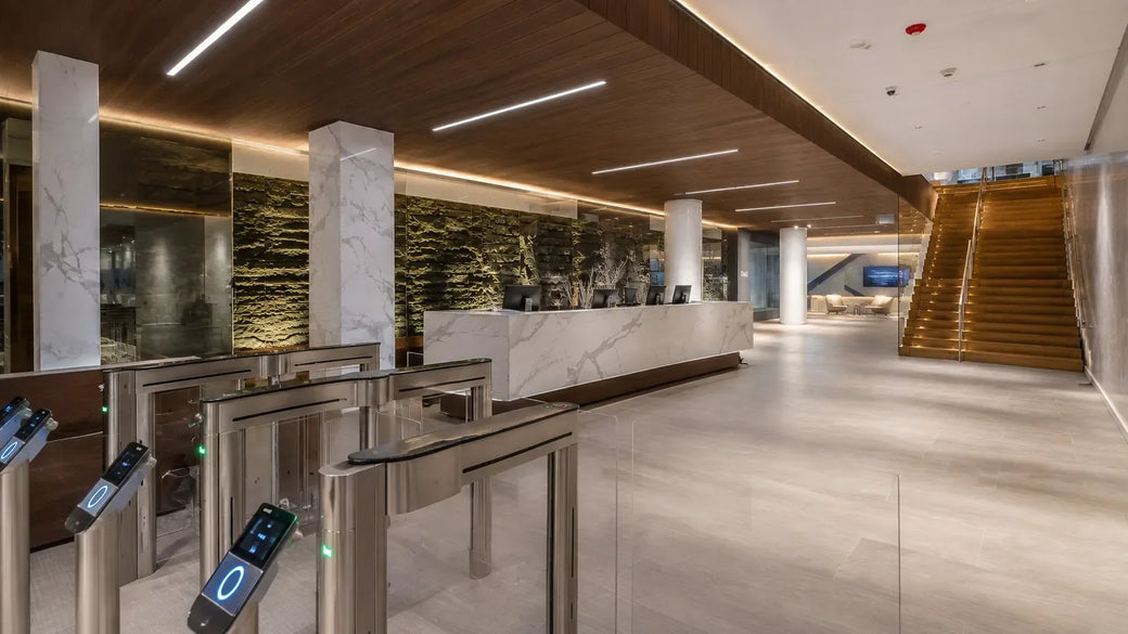 Slim linear recessed LED panels in a wood ceiling above an upscale hotel lobby reception desk