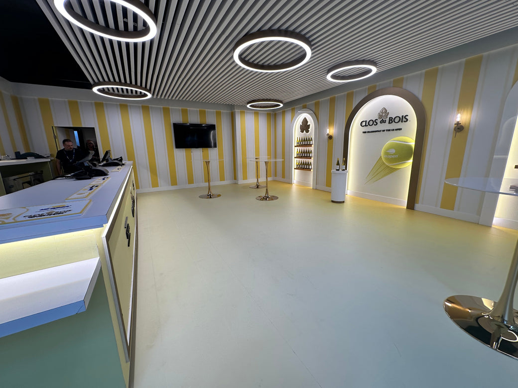White LED round pendant lights suspended above a temporary event wine bar with a slatted baffle ceiling