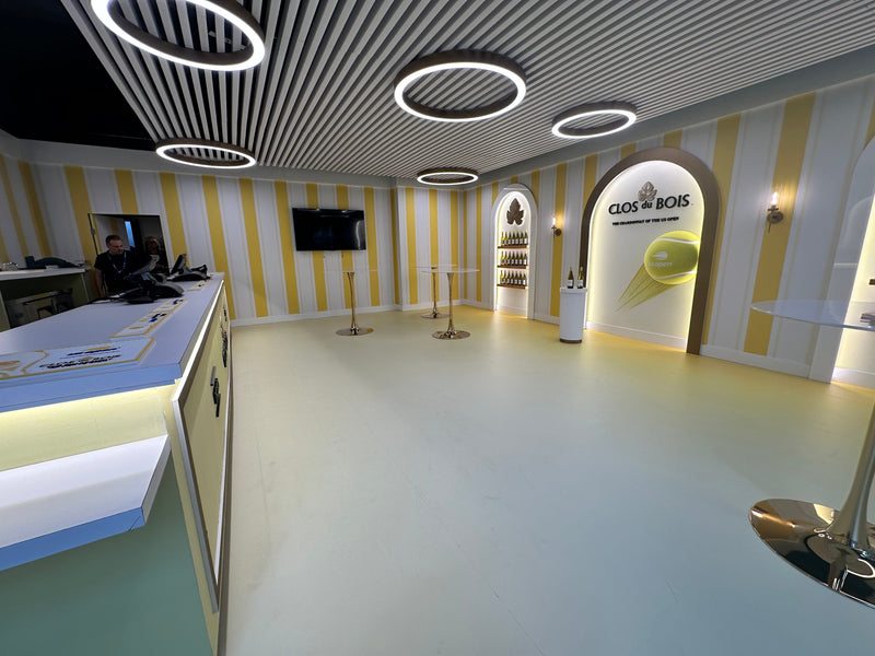 White LED round pendant lights suspended above a temporary event wine bar with a slatted baffle ceiling