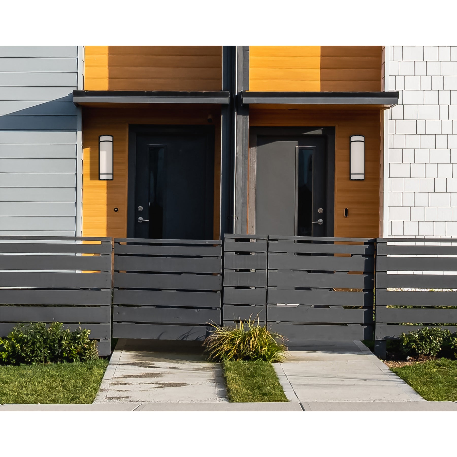 Modern house exterior with a gray front door and black fence.