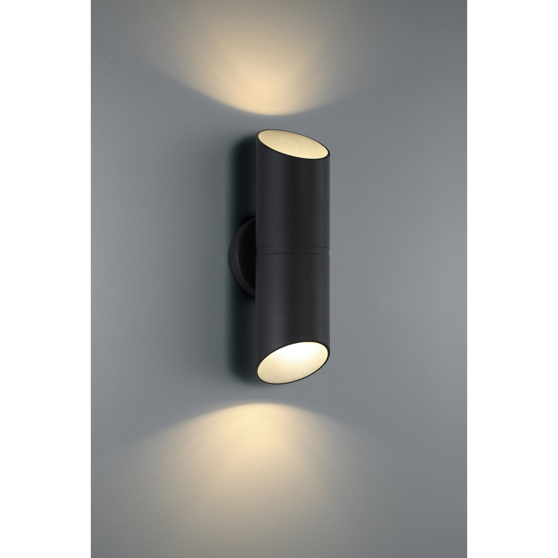 Black cylindrical wall light fixture on a gray wall
