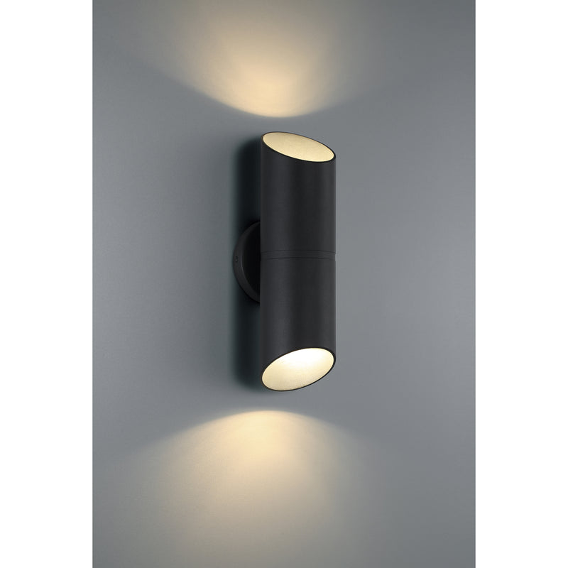 Black cylindrical wall light fixture on a gray wall