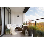 Modern outdoor living space with a sectional sofa, plants, and a view of trees and sky.