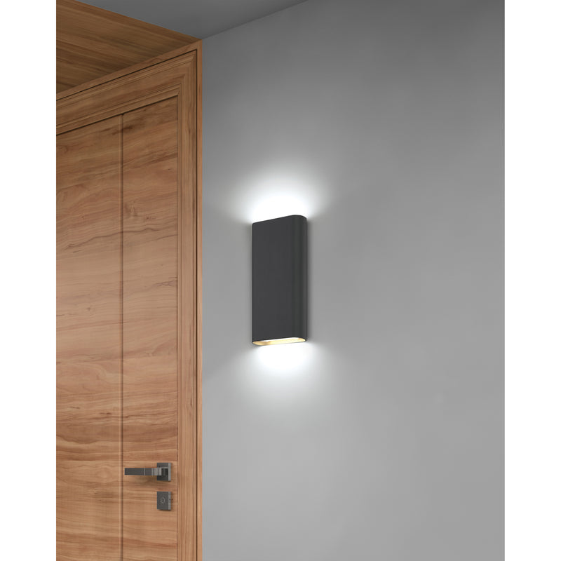Black wall-mounted light fixture on a gray wall next to a wooden door.