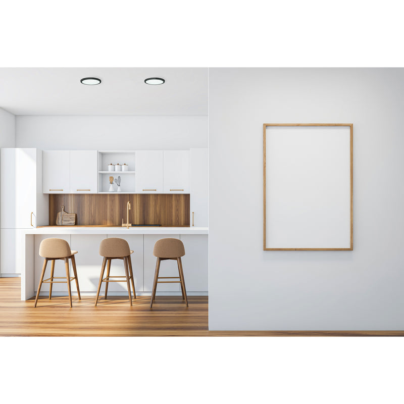 Modern kitchen with wooden bar stools and a framed poster on a white wall.