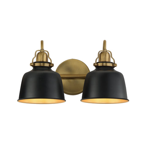 A two-light wall sconce with matte black bell-shaped shades and antique brass hardware, including a round backplate and decorative caps, shown against a plain white background.