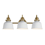 A three-light bathroom vanity light fixture with white dome-shaped glass shades and an antique brass horizontal bar and mounting hardware, shown against a plain white background.