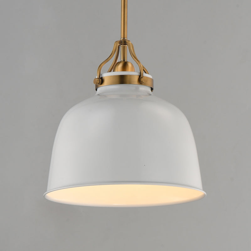 A modern pendant light with a large white dome-shaped shade, a warm white glowing interior, and antique brass hardware at the top, suspended against a solid gray background.