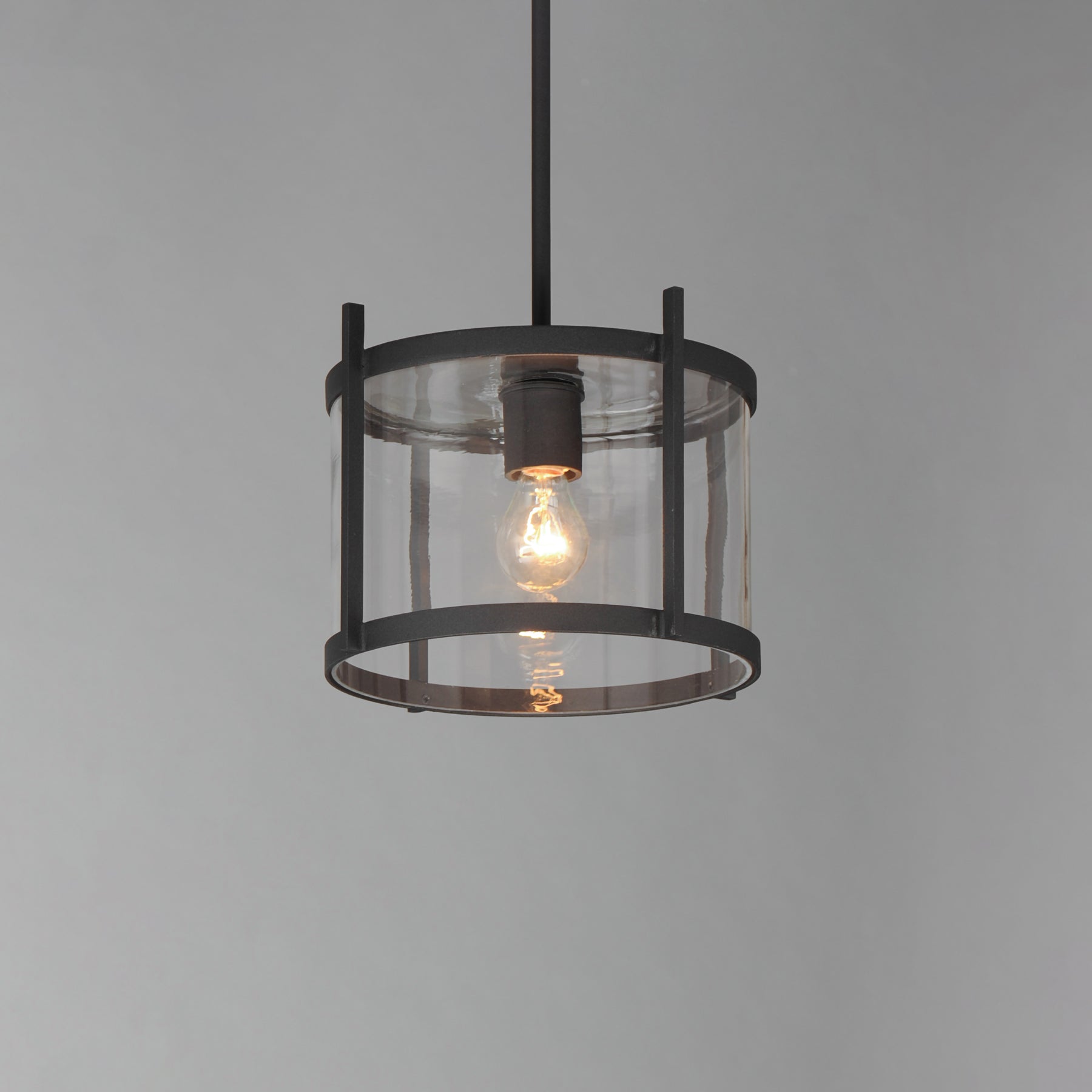 Pendant light with clear glass shade and black metal frame on a gray background