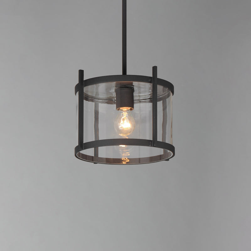 Pendant light with clear glass shade and black metal frame on a gray background