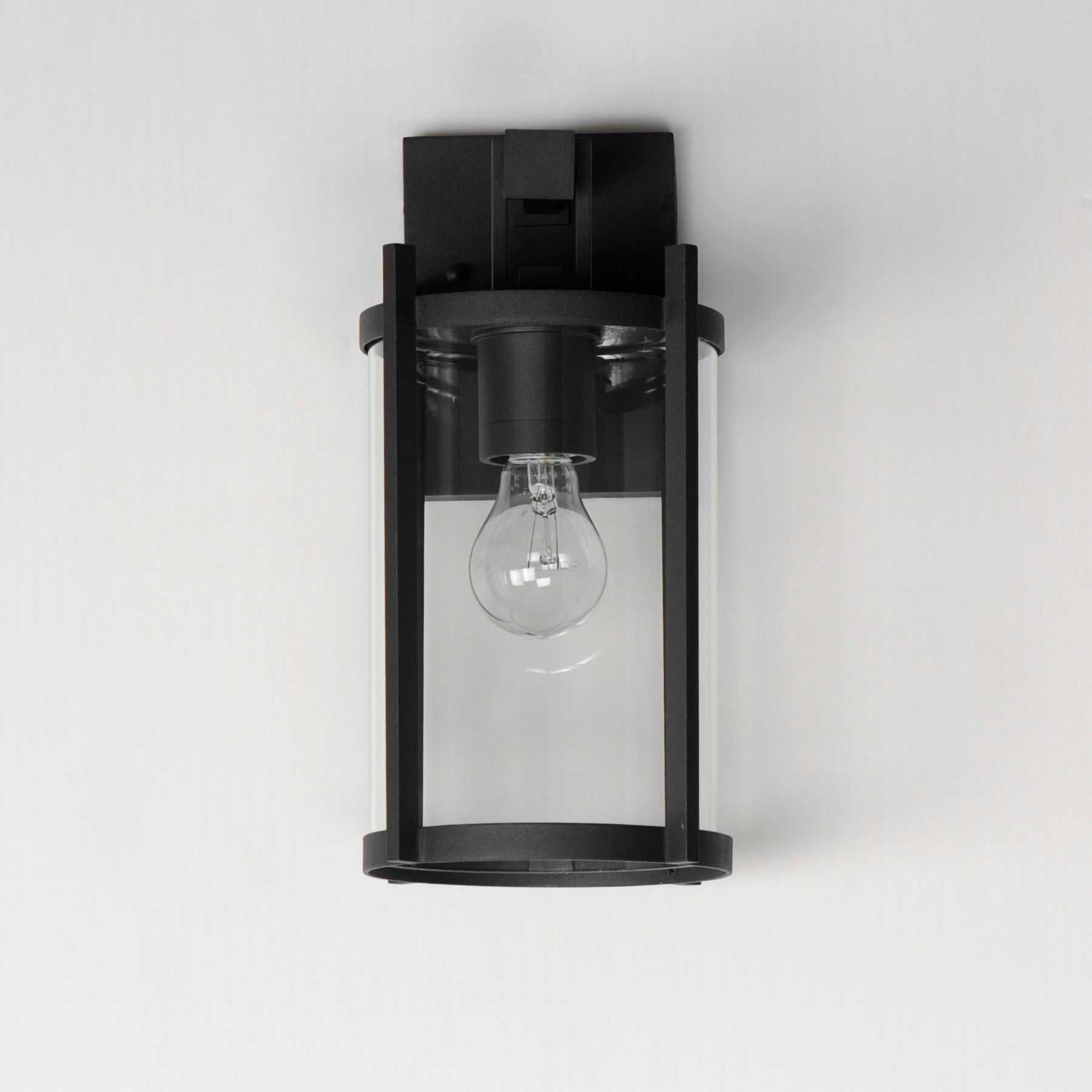 Black wall-mounted light fixture with a clear glass cover on a white background