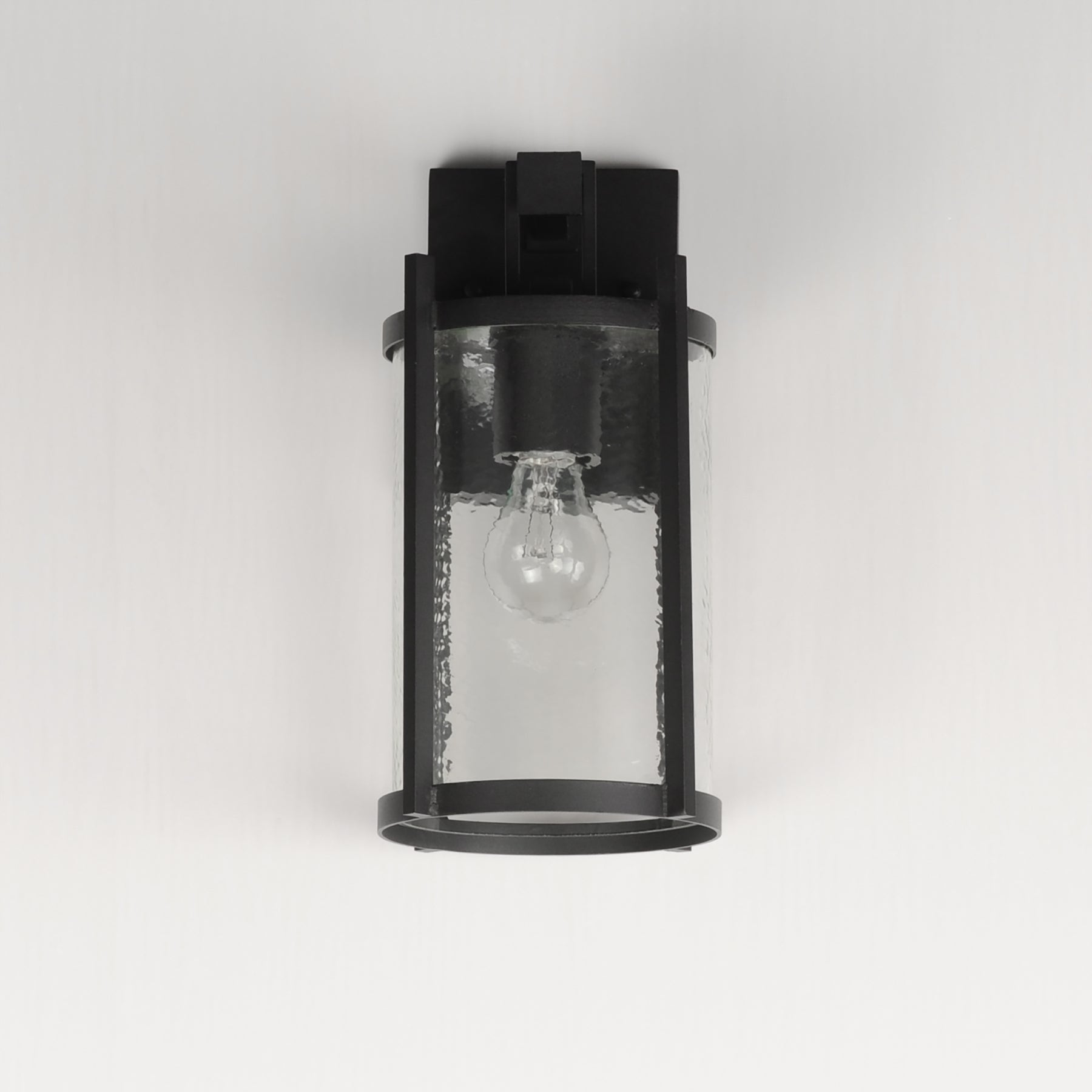 Black outdoor wall light fixture with clear glass cover on a white background