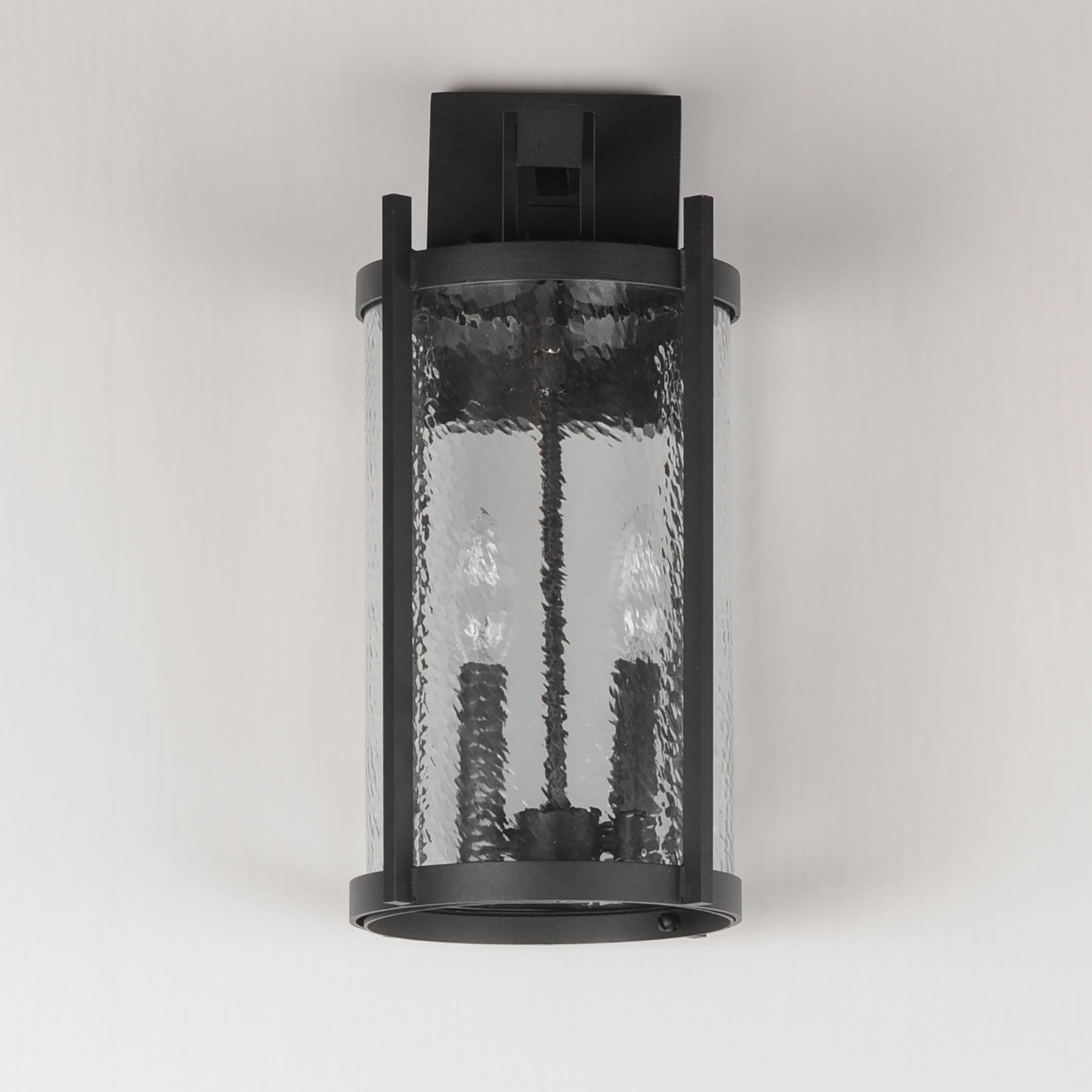 Black outdoor wall light fixture with textured glass on a white background