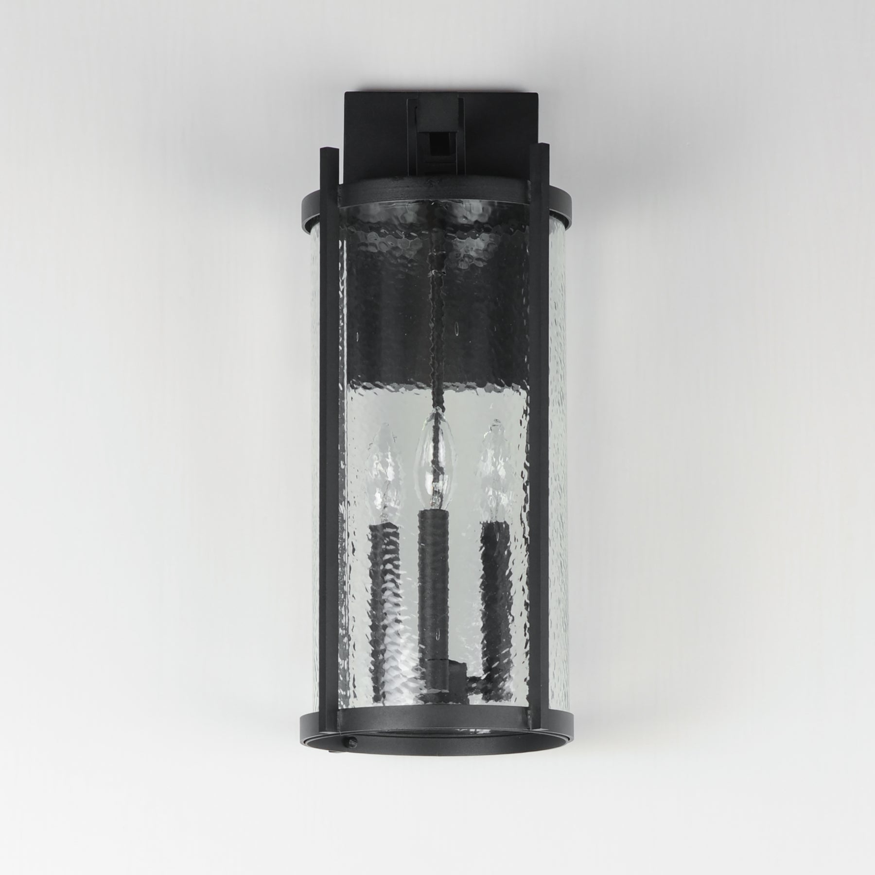 Black outdoor wall light fixture with clear glass cover on a white background