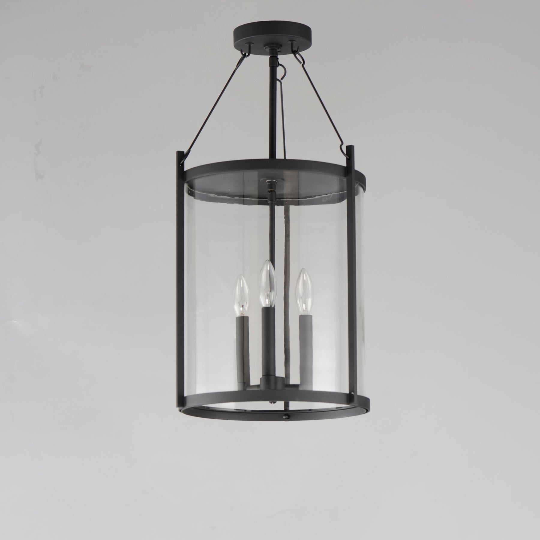 Black pendant light fixture with clear glass shade on a gray background