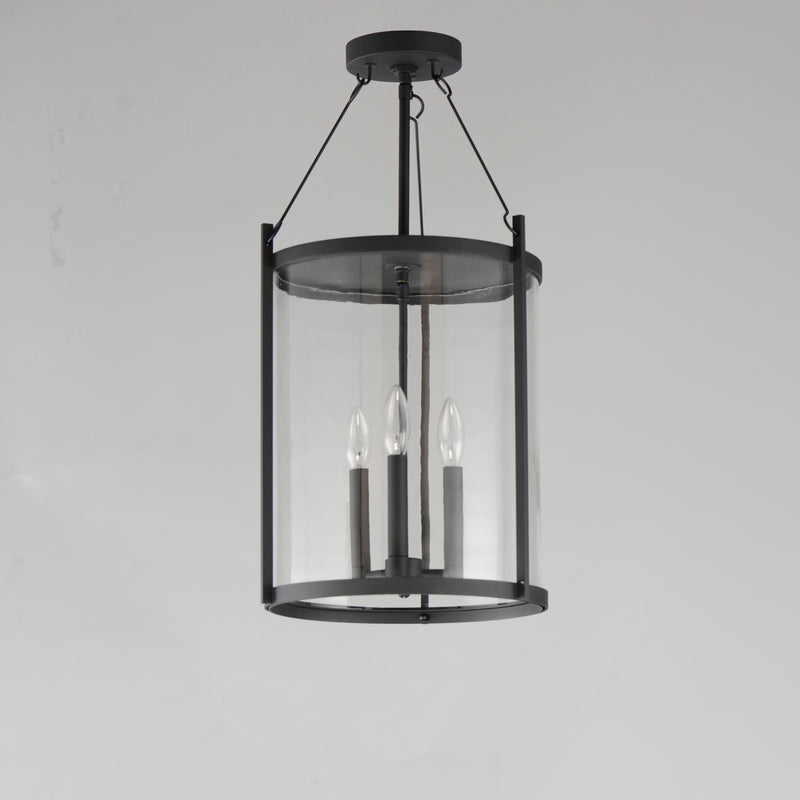 Black pendant light fixture with clear glass shade on a gray background