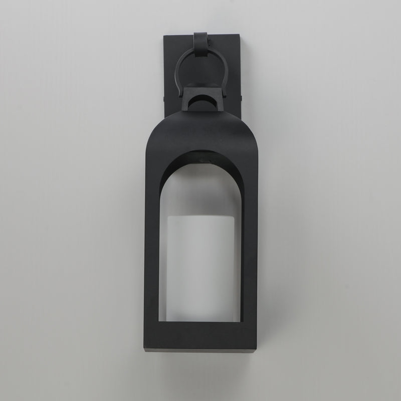 A matte black outdoor wall sconce with a lantern-style frame and a glass panel, shown against a neutral light gray background.