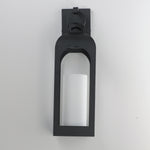 A modern black outdoor wall sconce with a frosted white cylindrical glass shade, mounted on a plain light gray wall.