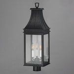 A black outdoor lantern-style wall light with three visible candle-style bulbs inside a rectangular glass enclosure, shown against a plain gray background.