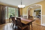 Dining room with wooden table and chairs, large window, and yellow walls.