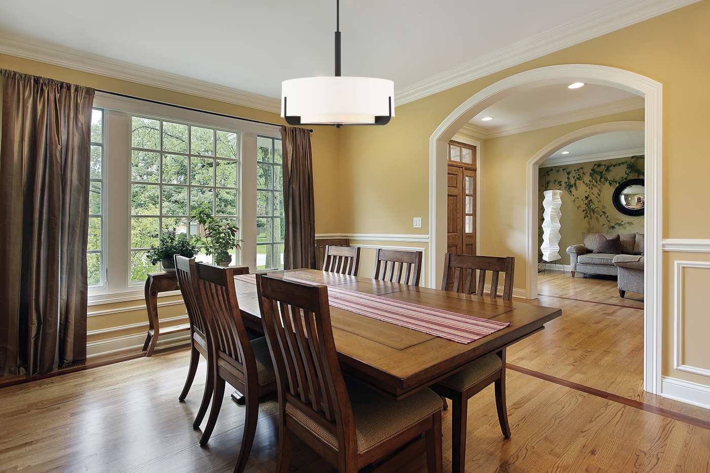 Dining room with wooden table and chairs, large window, and yellow walls.