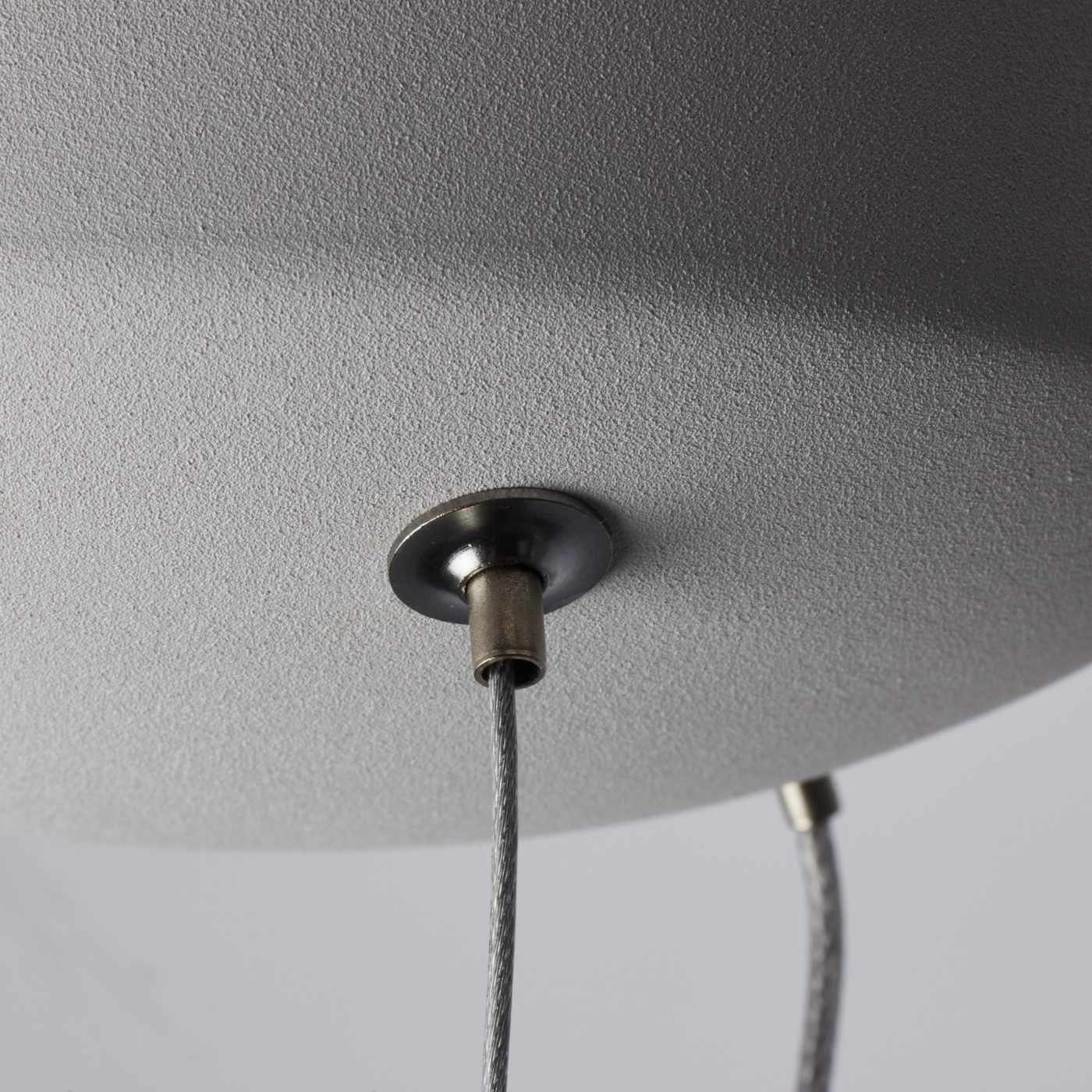Close-up of a ceiling light fixture with a textured gray shade and visible wiring.