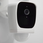 Smart home security camera mounted on a white wall