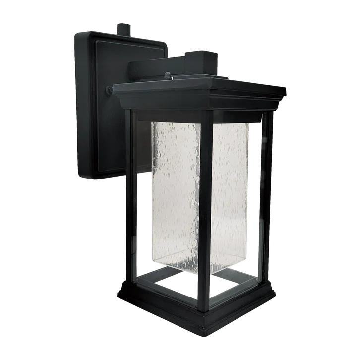 A black outdoor wall lantern light fixture with a textured clear glass shade, shown against a plain white background.