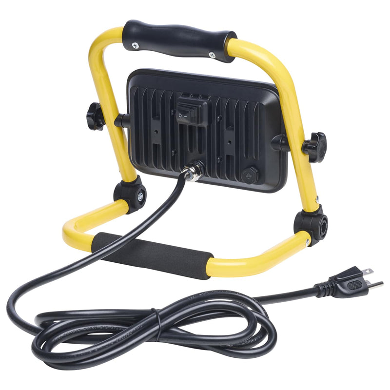A portable work light with a yellow metal frame, black handle, and black cooling fins on the back, shown with its attached black power cord on a white background.