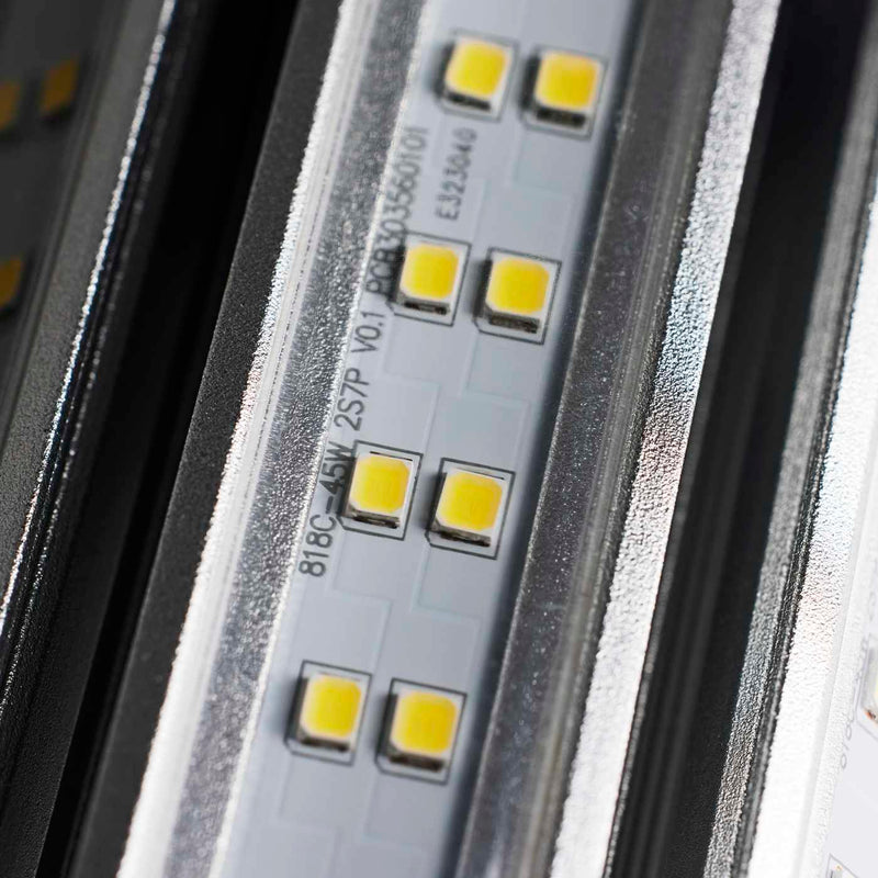 Close-up of an LED light strip showing multiple small yellow LED chips on a silver metal base with printed technical specifications.