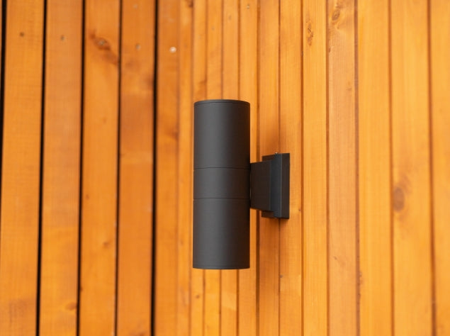 Outdoor cylinder light hanging on a wooden fence