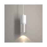 A modern cylindrical pendant light with a white upper section and a brushed nickel lower section, shown illuminated against a neutral gray wall.