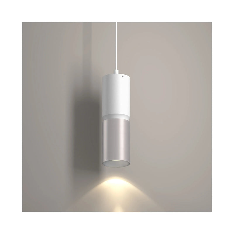 A modern cylindrical pendant light with a white upper section and a brushed nickel lower section, shown illuminated against a neutral gray wall.