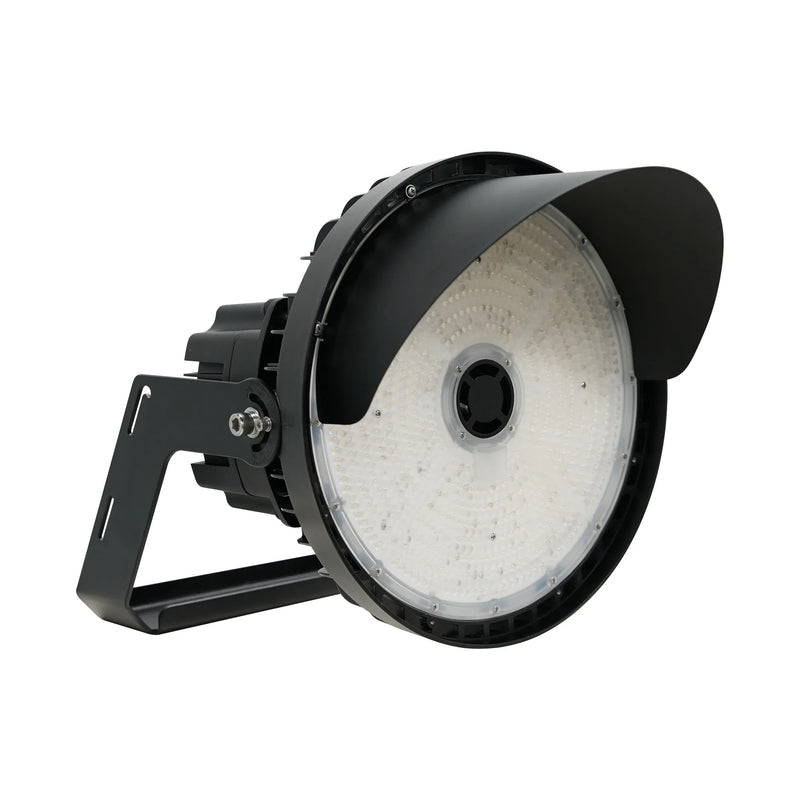 A black industrial LED stadium light with a protective hood and mounting bracket, shown from a three-quarters angle on a white background.