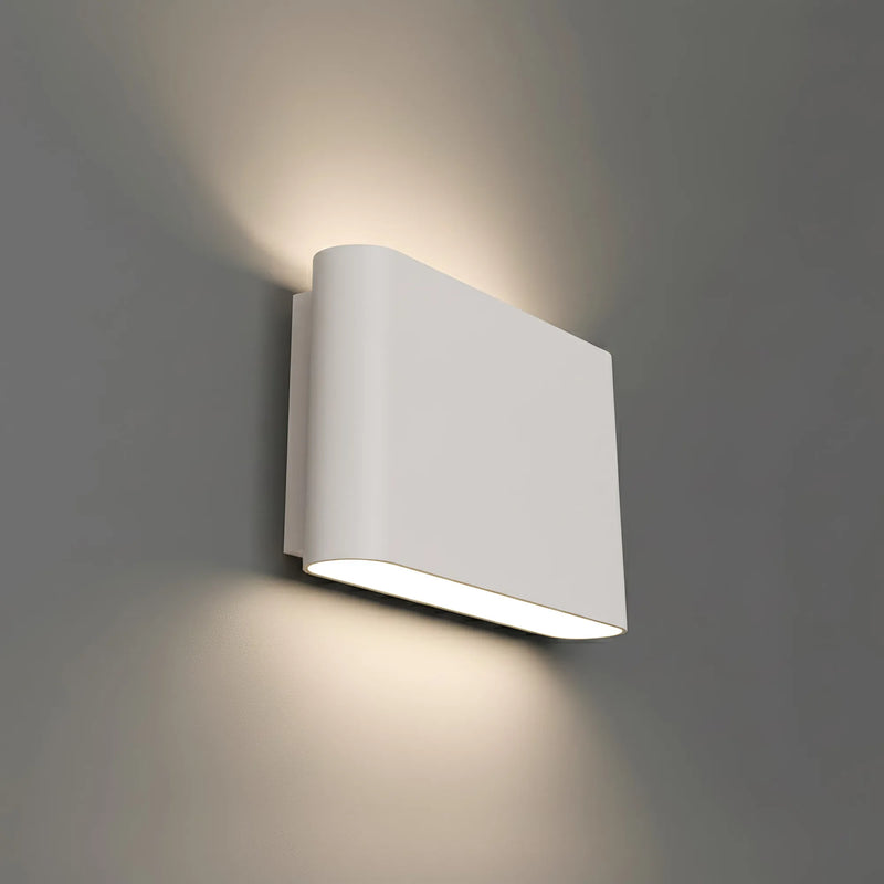 A modern white rectangular wall sconce light fixture mounted on a gray wall, casting a warm glow upwards and downwards.