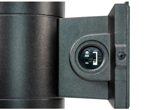 Close-up detail of a black cylindrical device with a side-mounted circular port or connector on a white background.